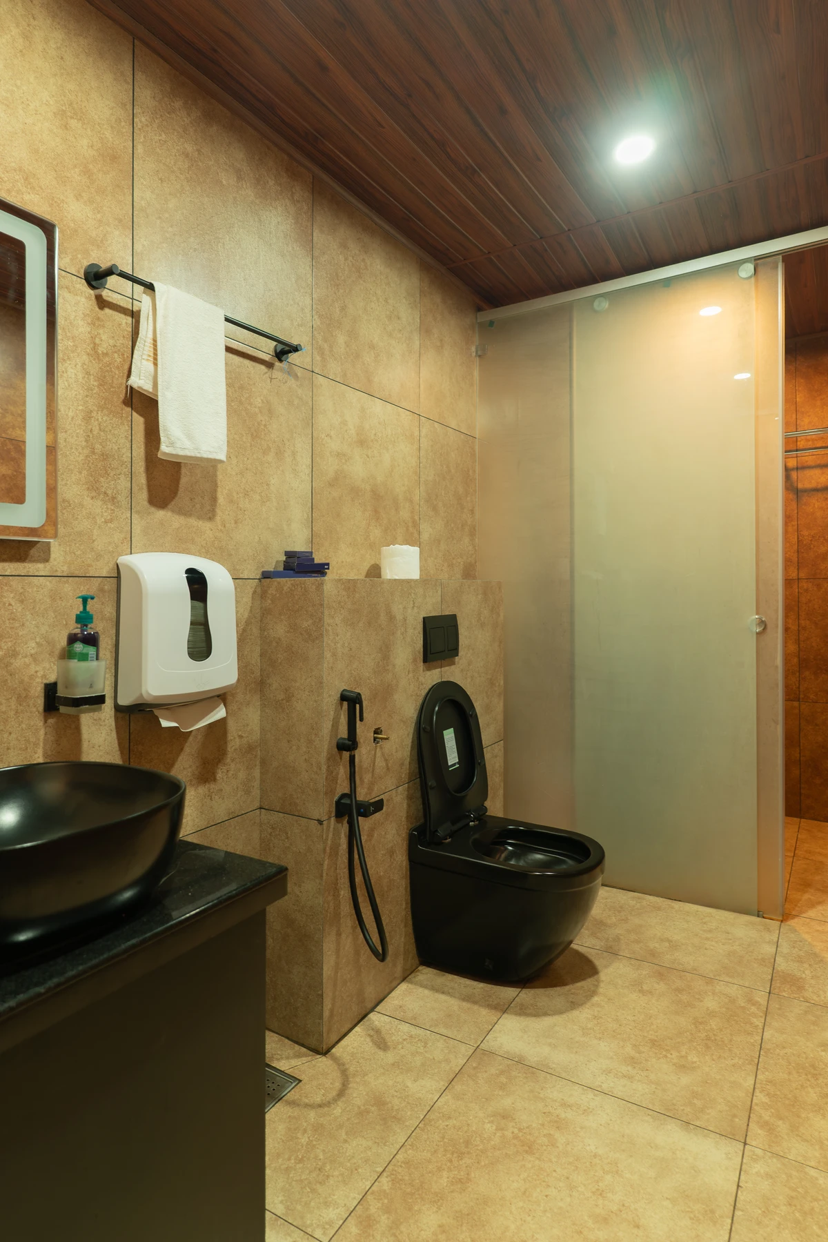 Modern shower area with a sleek black shower panel and textured tiles at boCHE 1000 Acre, one of the best resorts in Wayanad.