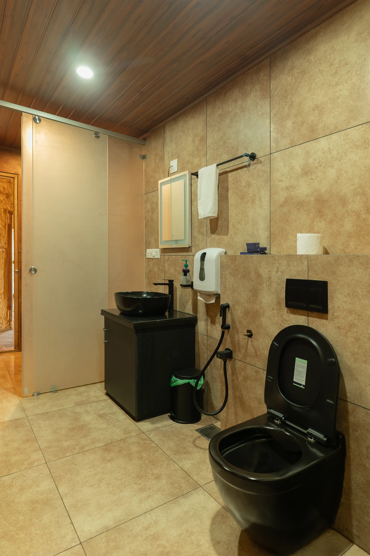 TModern shower area with a sleek black shower panel and textured tiles at boCHE 1000 Acre, one of the best resorts in Wayanad.