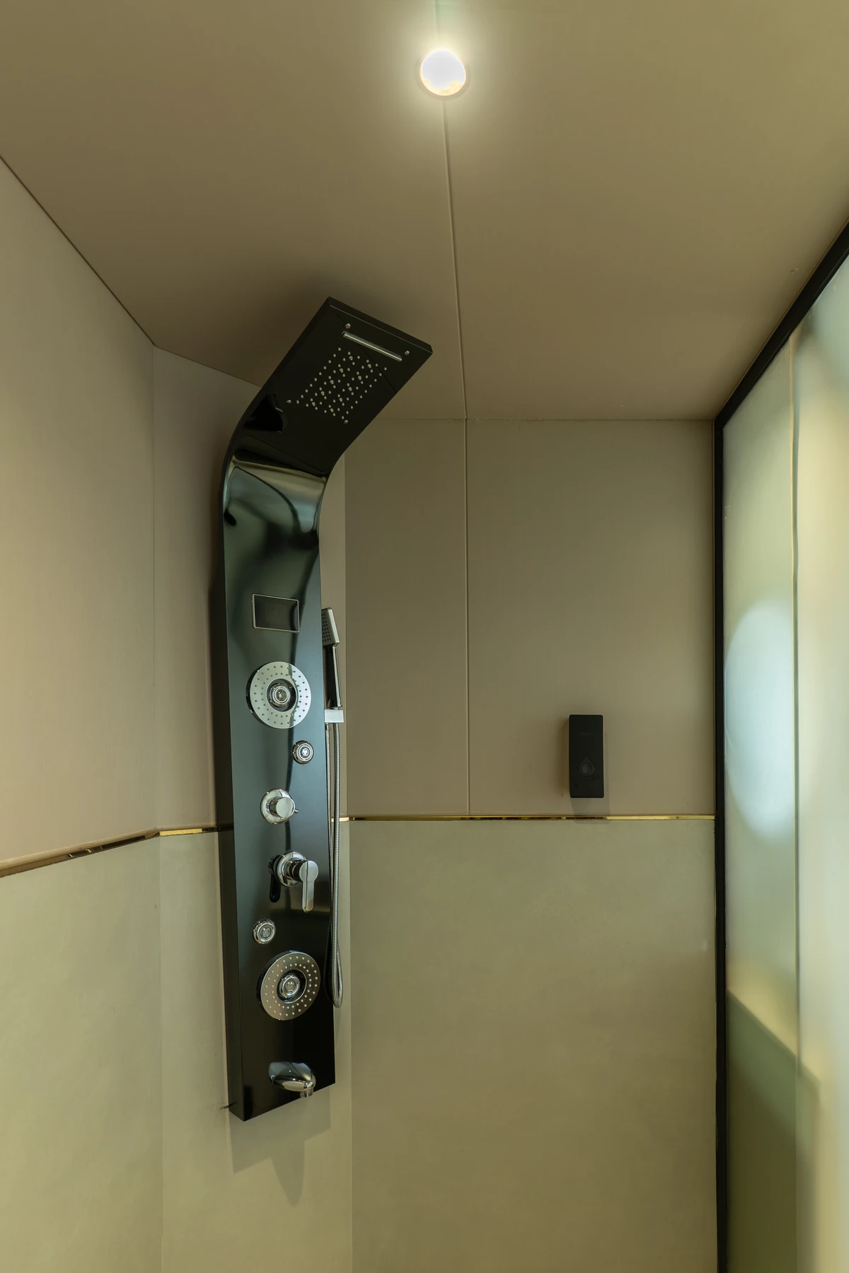 Sleek black multi-function shower panel in a modern stall at boCHE 1000 Acre, one of the best resorts in Wayanad.