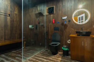 Modern wooden bathroom with a glass shower and LED mirror at boCHE 1000 Acre, one of the best resorts in Wayanad.