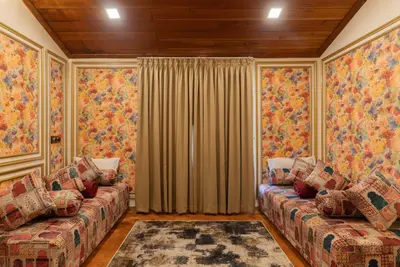 Cozy lounge room with patterned diwans and floral wallpaper at boCHE 1000 Acre, one of the best resorts in Wayanad.