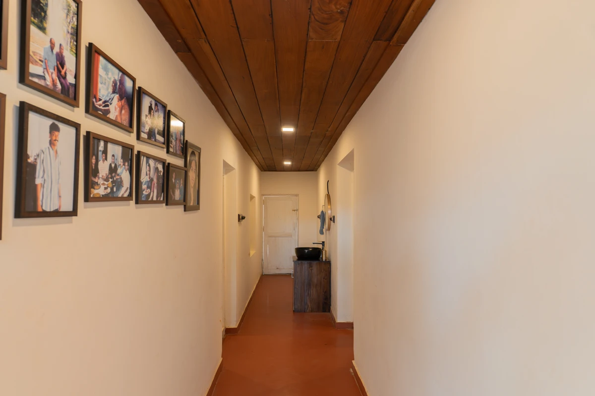 Elegant Hallway with Photo Gallery Elegant hallway with a photo gallery wall and wooden ceiling at boCHE 1000 Acre, one of the best resorts in Wayanad.